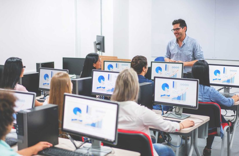 Instructor teaching a fiscal class to a group of people using computers